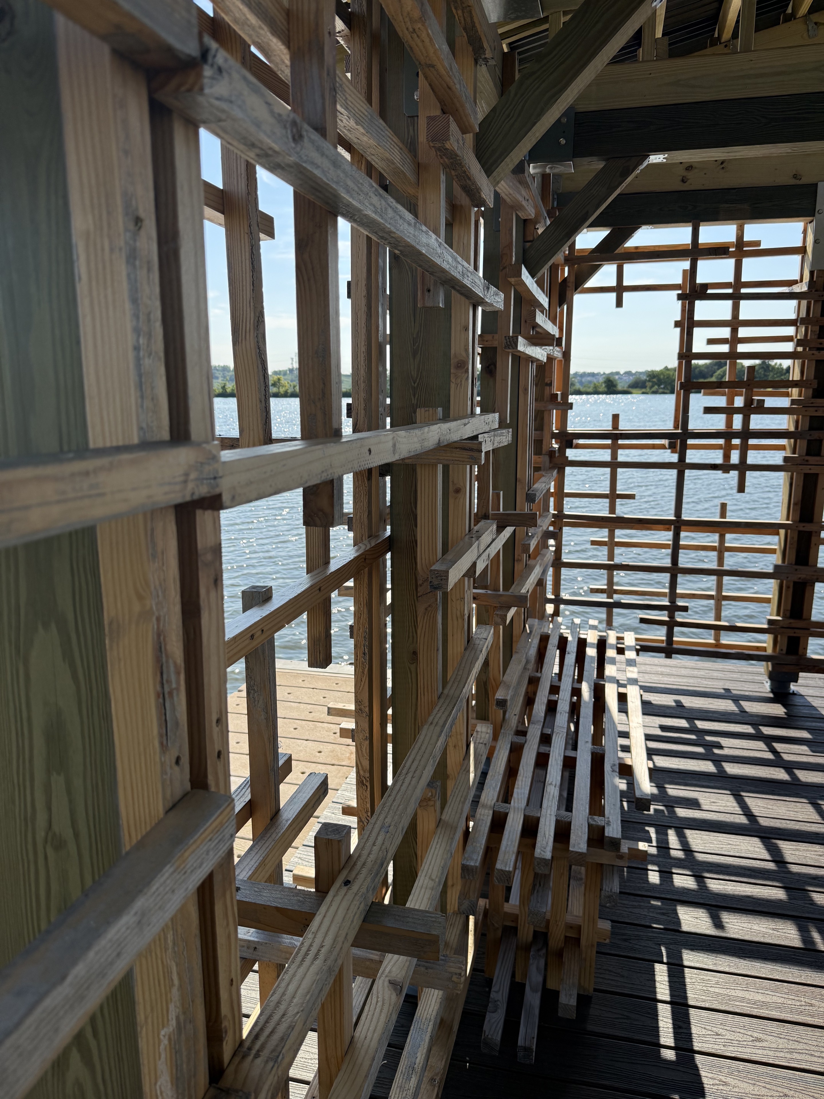 Close view through layered wood slats toward sunlight sparkling on the water.